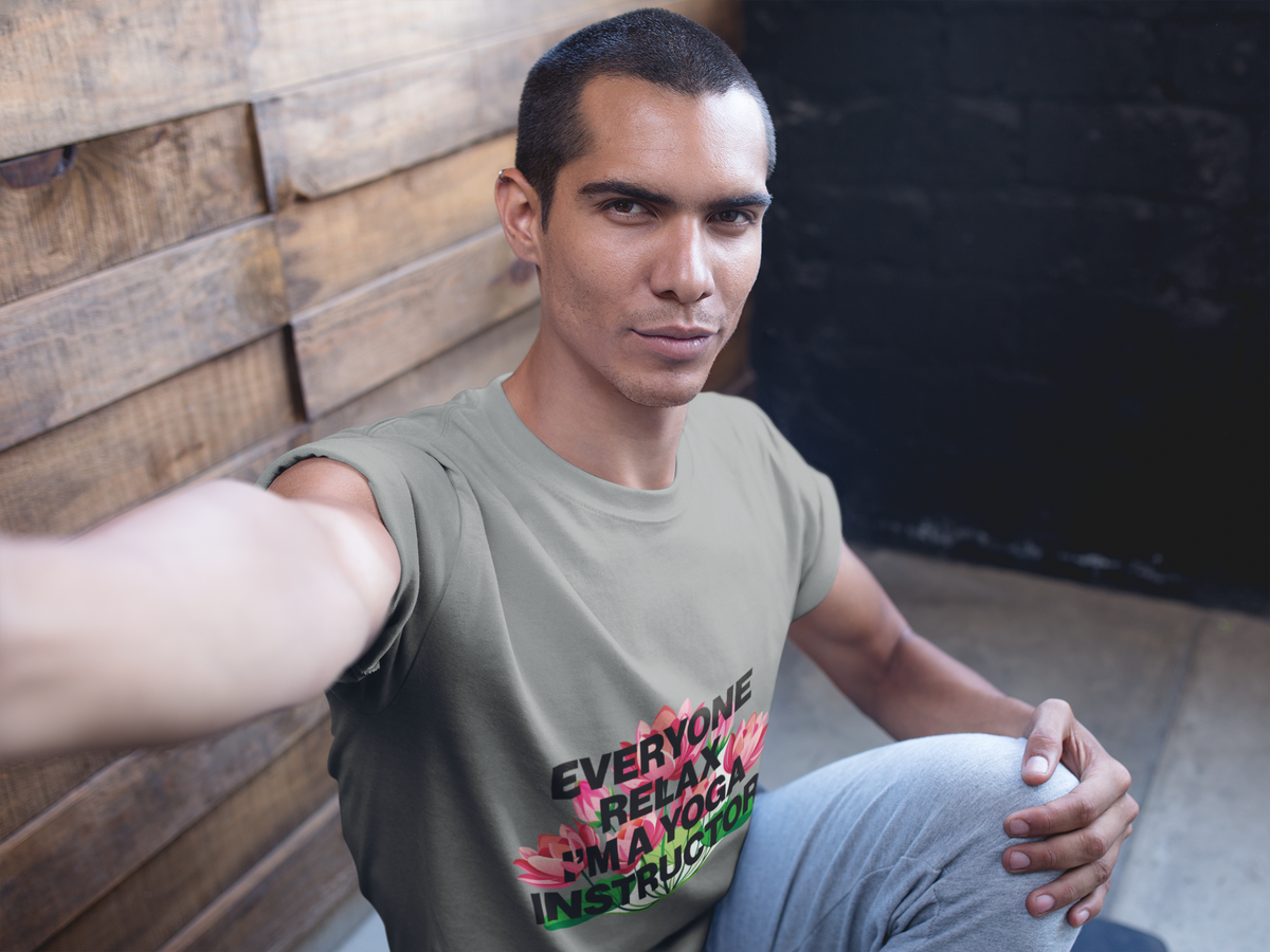 Man wearing a t-shirt with text sitting against a wooden wall.