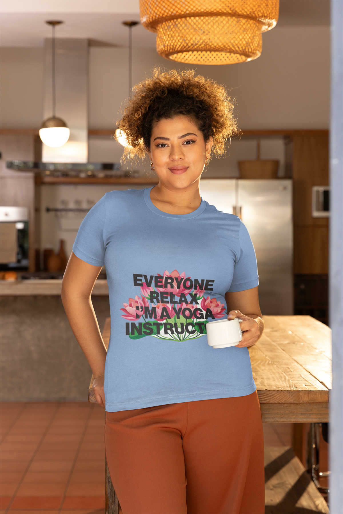 Woman wearing a blue t-shirt with text and flowers in a kitchen