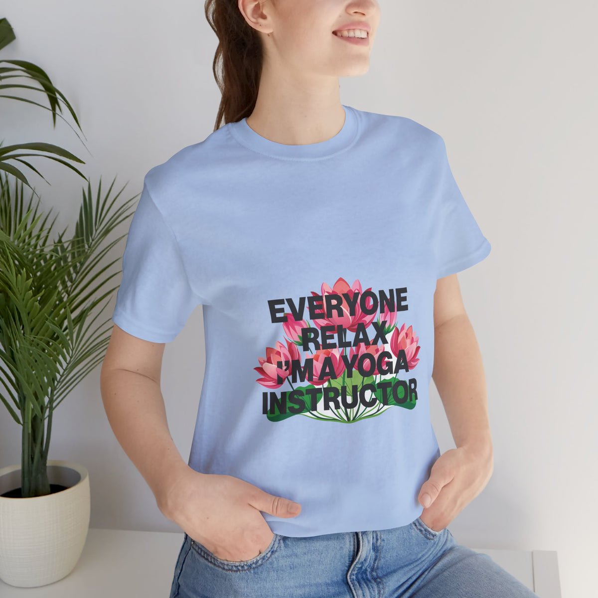 Person wearing a light blue t-shirt with a colorful graphic and text, standing indoors.